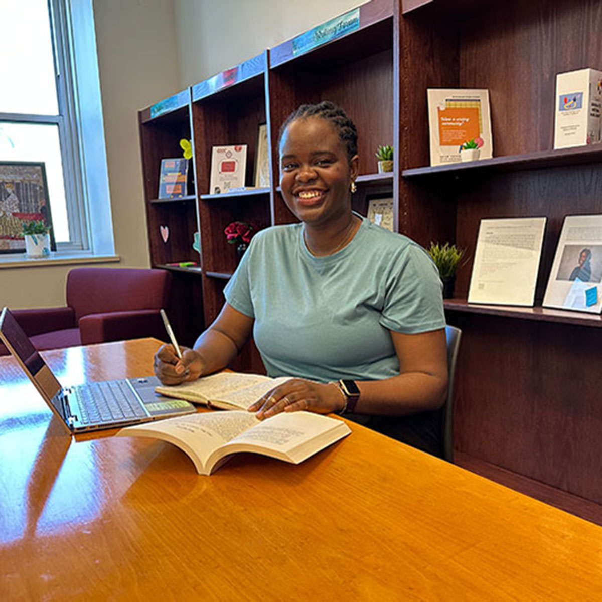 Damilola Oyedeji, an English-creative writing master's student, studying and writing in the Siceluff Hall Student Lounge.
