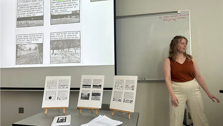 Emily Lewandowski, a English-creative writing master's student, presents her thesis in a classroom, showing written and illustrated panels of her graphic novel.