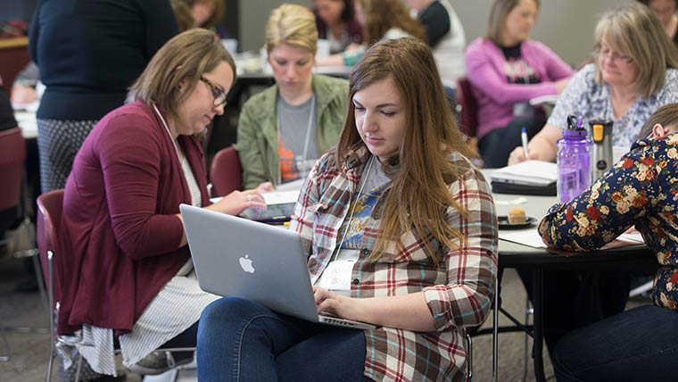 A college student types on their laptop during a professional development workshop.