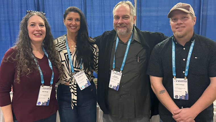 Four members of faculty, including Sara Burge, Jen Murvin, Michael Czyzniejewski and Joel Coltharp, gather for a group picture at their booth while representing the creative writing program at the Association of Writers and Writing Programs in Baltimore.
